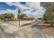Wide shot showcasing long driveway behind a chain-link fence and gate, and desert landscaping at 5202 Willis St, North Las Vegas, NV 89031