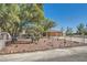 Spacious front yard featuring mature trees, rock landscaping, and secure fencing at 5202 Willis St, North Las Vegas, NV 89031