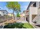 Wide backyard shot of home and neighboring buildings featuring patio and artificial lawn at 7047 Sombra Way, Las Vegas, NV 89113