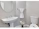 Half bath featuring a pedestal sink, toilet, and decorative mirror at 7047 Sombra Way, Las Vegas, NV 89113