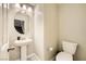 A clean, compact bathroom with a pedestal sink, toilet, and neutral decor offers functionality at 707 Cottonwood Hill Pl, Henderson, NV 89011