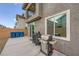 A backyard patio features a barbecue grill and blue recycling bins against a stucco wall at 707 Cottonwood Hill Pl, Henderson, NV 89011