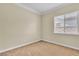 A beige bedroom with a ceiling fan, carpeted floors, and a large window with blinds at 7505 Java Sparrow St, North Las Vegas, NV 89084