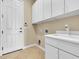 Laundry room with sink, cabinets, tile floor and direct access to the outside at 7505 Java Sparrow St, North Las Vegas, NV 89084