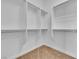 Bright walk-in closet with white shelving and rods for hanging clothes at 7505 Java Sparrow St, North Las Vegas, NV 89084