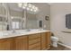 Bright bathroom featuring double sinks, light wood cabinets, and a large mirror at 7669 Fieldfare Dr, North Las Vegas, NV 89084