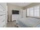 Comfortable bedroom featuring a television, white furniture, and a window with plantation shutters at 7669 Fieldfare Dr, North Las Vegas, NV 89084