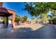 Spacious backyard featuring a built-in grill, covered patio, manicured trees and plants, and textured concrete flooring at 936 Viscanio Pl, Las Vegas, NV 89138
