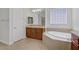Well-lit bathroom with soaking tub, glass block window, and a wood vanity at 936 Viscanio Pl, Las Vegas, NV 89138