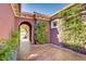 Inviting front entrance with an arched doorway and decorative concrete, enhanced by lush greenery and a glimpse of the neighborhood at 936 Viscanio Pl, Las Vegas, NV 89138