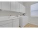 Functional laundry room with white cabinets, utility sink, washer, and dryer for efficient household chores at 936 Viscanio Pl, Las Vegas, NV 89138