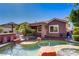 Beautiful outdoor area with sparkling pool, rock waterfall, lush greenery, and covered patio at 936 Viscanio Pl, Las Vegas, NV 89138