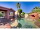 Gorgeous backyard features a pool with a waterfall, bar area, and mature palm trees at 936 Viscanio Pl, Las Vegas, NV 89138