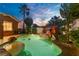 Resort-style pool featuring a rock waterfall feature, lush landscaping, and pristine water under a twilight sky at 936 Viscanio Pl, Las Vegas, NV 89138