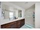 Bathroom featuring double sinks, dark wood cabinets, walk-in shower and large mirror at 10204 Kern Peak St, Las Vegas, NV 89166