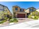 Charming two-story home with desert landscaping, a red garage door, and a brick-paved driveway at 10939 Cheshire Woods Ave, Las Vegas, NV 89166