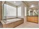 Primary bathroom highlighting a soaking tub, glass block window, large vanity, and tile floors at 11527 Morning Grove Dr, Las Vegas, NV 89135