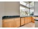 Corner wet bar with wood cabinets, granite countertops, a view of the outside, and modern fixtures at 11527 Morning Grove Dr, Las Vegas, NV 89135
