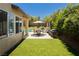 Well-manicured backyard featuring an outdoor dining set, BBQ, grassy area, and a sparkling pool at 145 Austin Rose Ave, Henderson, NV 89002