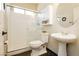 Compact bathroom featuring a shower, toilet, and pedestal sink, with dark floors at 145 Austin Rose Ave, Henderson, NV 89002