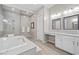 Elegant bathroom with a soaking tub, glass-enclosed shower, double vanity, and natural light at 16 Via Stefano, Henderson, NV 89011