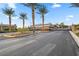 A paved entrance into a private community with palm trees, a metal gate, and desert landscaping at 16 Via Stefano, Henderson, NV 89011