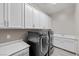 Laundry room with sink, modern washer and dryer, and upper and lower cabinets at 16 Via Stefano, Henderson, NV 89011