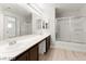 Bathroom featuring double sinks, wood cabinets, a large mirror, and a glass shower at 3526 Harbor Tides St, Las Vegas, NV 89147