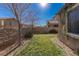A view of the home's backyard featuring green grass, trees, and a brick perimeter at 436 Trevinca St, Las Vegas, NV 89138