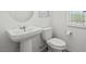 Bright half bathroom features pedestal sink, toilet, and window with blind, on decorative tile flooring at 4526 Cloudrest Peak St, North Las Vegas, NV 89031