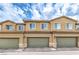 Inviting townhouse showcasing multiple windows, prominent garage doors, and manicured landscaping at 49 Alamere Falls Dr, Las Vegas, NV 89138
