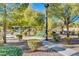 Park features a walking path, mature trees, trimmed bushes, and a green bench for relaxing in a natural setting at 4937 Teal Petals St, North Las Vegas, NV 89081