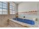 Luxurious blue tiled jetted tub with seashell design and natural light through the window at 4998 Schumann Dr, Las Vegas, NV 89146