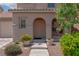 Charming home entrance with arched entryway, well-manicured landscaping, and a covered porch at 5001 Volcanic Rock Ln, Las Vegas, NV 89122