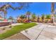 Spacious backyard featuring artificial turf, concrete pavers, murals, palm trees, and a hot tub at 5626 Deer Creek Falls Ct, Las Vegas, NV 89118