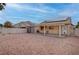Wide view of private backyard featuring stone landscaping, covered patio, solar panels, and storage shed at 6436 Point Break St, North Las Vegas, NV 89084