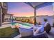 Beautiful backyard with pool, spa, lounge area, and pergola with outdoor lighting at dusk at 10718 Desert Heights Ave, Las Vegas, NV 89135