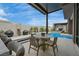 Beautiful outdoor living area with a dining table, bar seating, pool and pergola in a modern backyard design at 10718 Desert Heights Ave, Las Vegas, NV 89135
