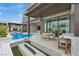 Modern outdoor living space featuring a sleek pool, fire pit, dining table and bar with ample seating at 10718 Desert Heights Ave, Las Vegas, NV 89135