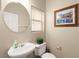 Cozy powder room with a round mirror, small sink, and framed artwork at 11135 Abbeyfield Rose Dr, Henderson, NV 89052