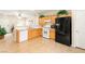 Well-lit kitchen with wooden cabinets, white appliances, and a sleek black refrigerator at 11135 Abbeyfield Rose Dr, Henderson, NV 89052