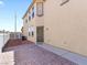 Side view of a tan two-story home with a brick patio and side door at 1124 Aspen Cliff Dr, Henderson, NV 89011