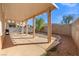 View of a backyard featuring a covered patio, gravel landscaping, and a block wall fence under a bright blue sky at 1813 Arch Stone Ave, North Las Vegas, NV 89031