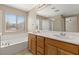 Well-lit bathroom featuring a double sink vanity, tub, and separate glass shower with a large mirror at 1813 Arch Stone Ave, North Las Vegas, NV 89031