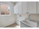 Convenient laundry room features white cabinets, sink, and a window for natural light at 1964 Oliver Springs St, Henderson, NV 89052