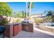 Outdoor kitchen with built-in barbecue, refrigerator, counter space, and lush landscaping at 204 N Ring Dove Dr, Las Vegas, NV 89144