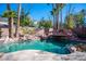 Backyard pool with rock features, a slide, and lush palm trees, perfect for outdoor enjoyment at 204 N Ring Dove Dr, Las Vegas, NV 89144