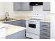 Corner view of a kitchen with grey cabinets and white appliances and countertops at 2191 Bay Club Dr # 102, Laughlin, NV 89029