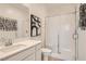 Bright bathroom featuring a modern vanity, glass shower, and stylish artwork, with an overall minimalist design at 242 White Crest Peak Ave, Henderson, NV 89015