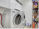 This laundry room features newer washer and dryer units, and built-in shelving for storage at 2613 Velodrome Ct, Henderson, NV 89044